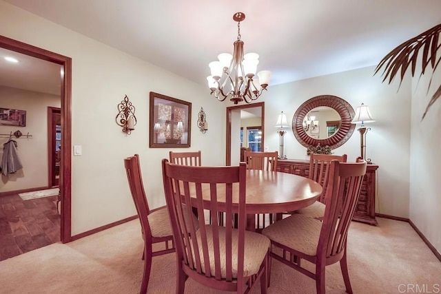 dining area featuring a chandelier, light colored carpet, and baseboards