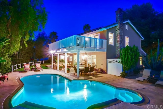 pool at twilight with an outdoor pool and a patio