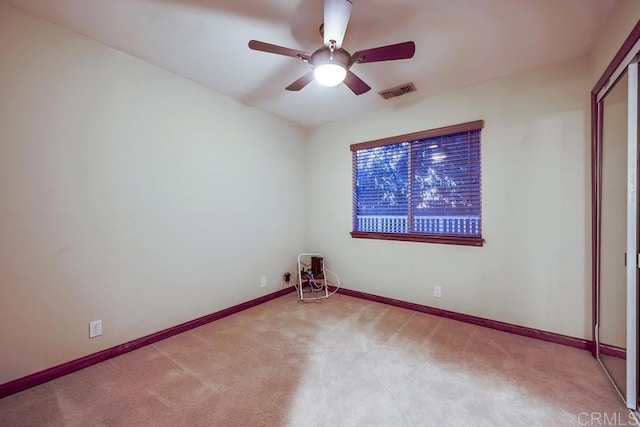 carpeted empty room with visible vents, baseboards, and ceiling fan