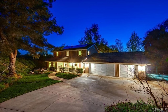 traditional home featuring a garage, a lawn, solar panels, and driveway