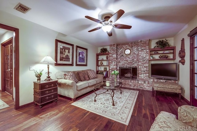 living room featuring wood finished floors, baseboards, visible vents, a ceiling fan, and a fireplace