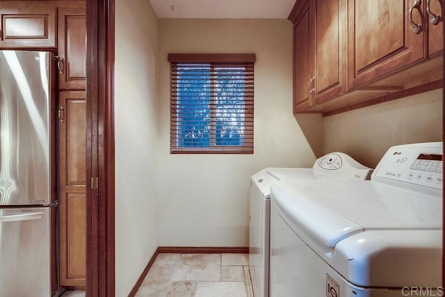 laundry area with stone tile flooring, cabinet space, baseboards, and separate washer and dryer