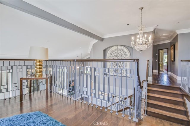 corridor with an inviting chandelier, lofted ceiling with beams, wood finished floors, and ornamental molding