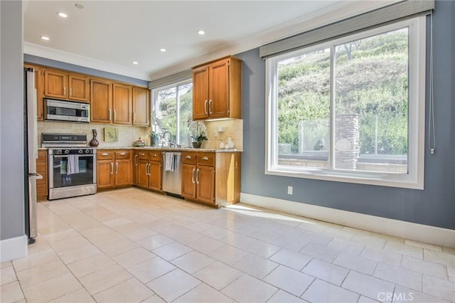 kitchen with decorative backsplash, baseboards, appliances with stainless steel finishes, and brown cabinetry