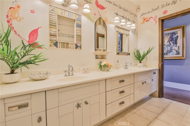 full bathroom featuring double vanity, baseboards, and a sink