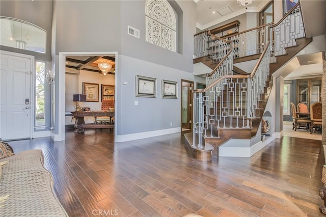 entryway featuring stairway, wood finished floors, visible vents, baseboards, and a high ceiling