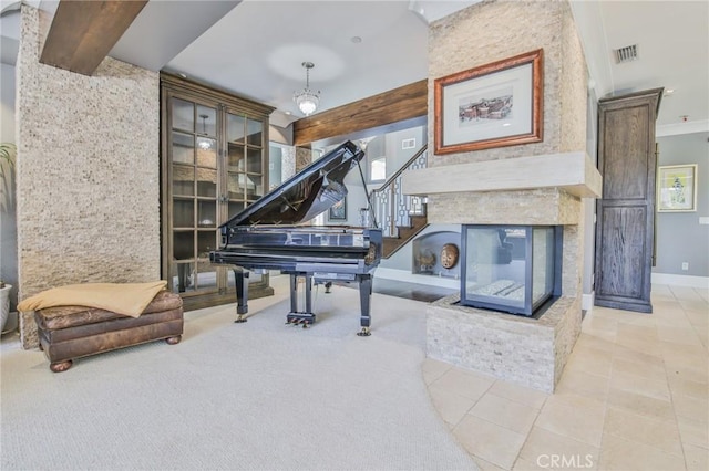 living area featuring visible vents, baseboards, a multi sided fireplace, beamed ceiling, and stairway