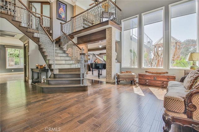 interior space with ornamental molding, wood finished floors, stairway, baseboards, and a towering ceiling