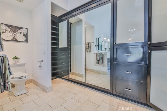 bathroom with tile patterned flooring, toilet, and baseboards