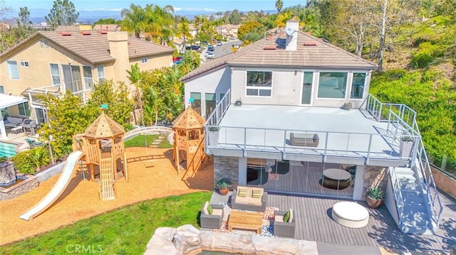 rear view of house featuring stucco siding and a playground