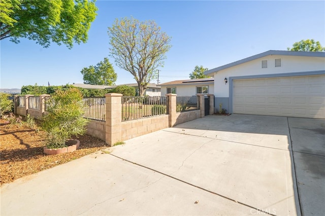 single story home with concrete driveway, an attached garage, a fenced front yard, and stucco siding