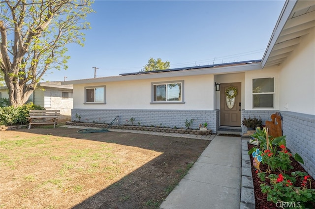 property entrance featuring stucco siding, brick siding, and a lawn