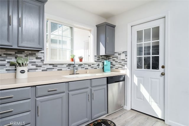 kitchen featuring a sink, gray cabinetry, decorative backsplash, and stainless steel dishwasher