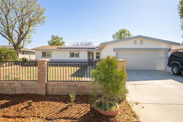 single story home with stucco siding, driveway, a fenced front yard, roof mounted solar panels, and a garage