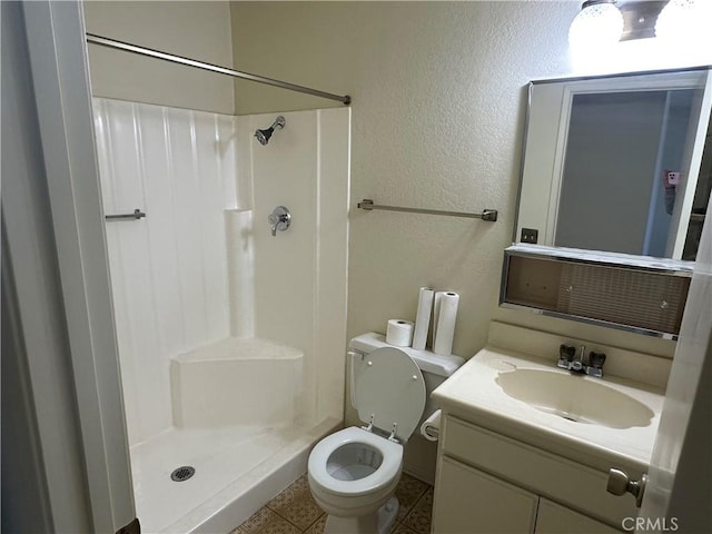 bathroom featuring toilet, a stall shower, vanity, and a textured wall