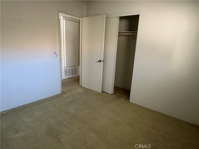 unfurnished bedroom featuring visible vents, light carpet, and a closet