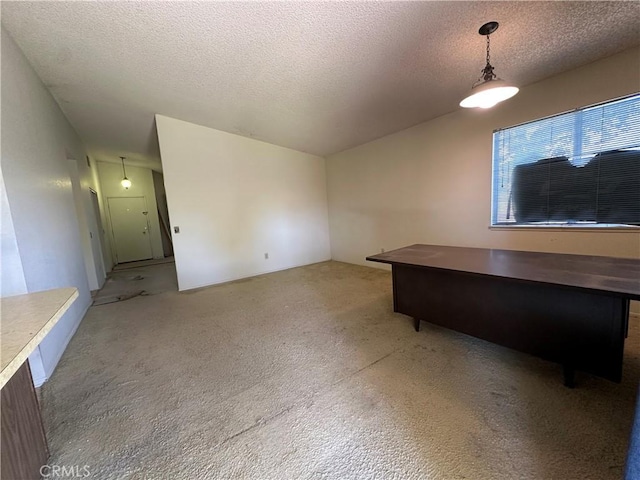 unfurnished office featuring a textured ceiling, vaulted ceiling, and light carpet