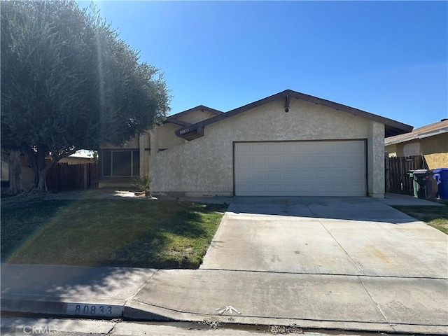 single story home featuring a front yard, an attached garage, fence, and stucco siding