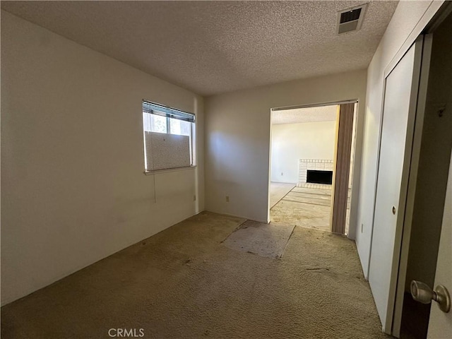 unfurnished room featuring a fireplace, visible vents, and a textured ceiling