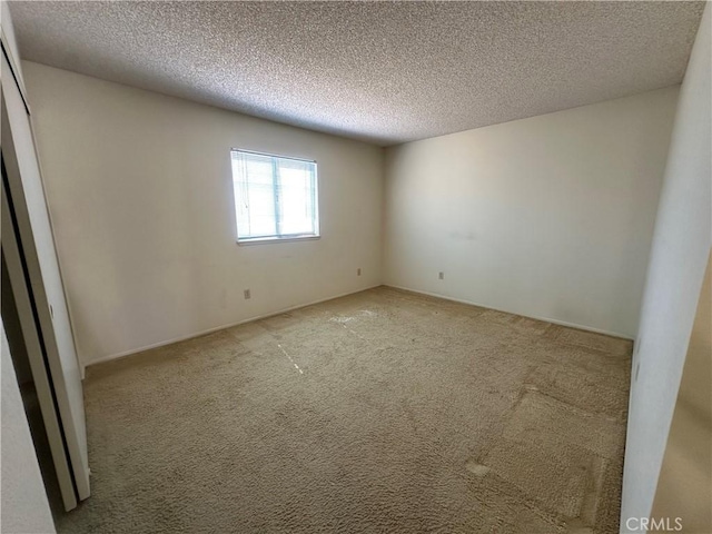 unfurnished room featuring a textured ceiling and light carpet