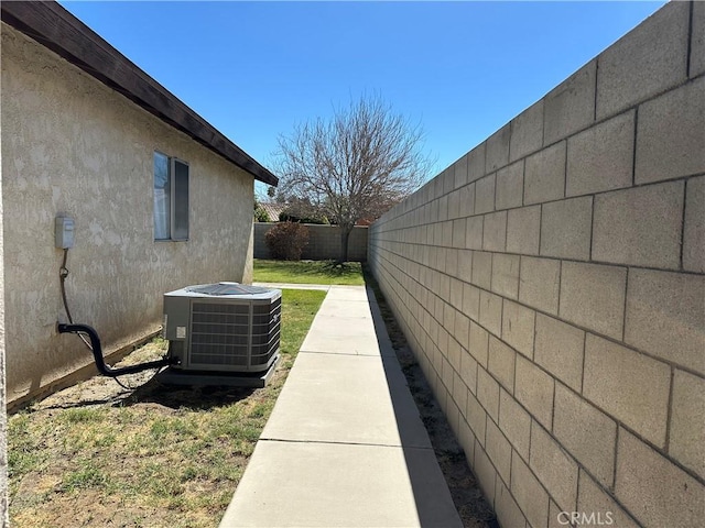 view of side of property featuring central AC unit, a fenced backyard, and stucco siding