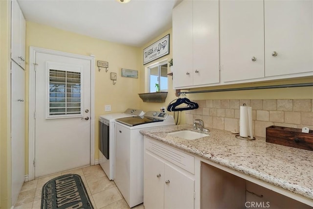laundry room with light tile patterned flooring, washing machine and clothes dryer, a sink, and cabinet space