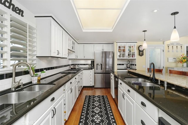kitchen with dark wood-style floors, a sink, stainless steel fridge, and white cabinets