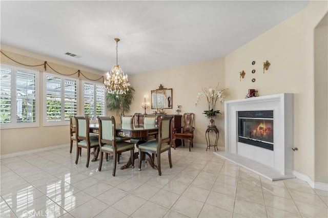 dining room featuring light tile patterned floors, visible vents, and a glass covered fireplace