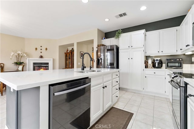 kitchen with visible vents, a sink, a glass covered fireplace, white cabinetry, and appliances with stainless steel finishes