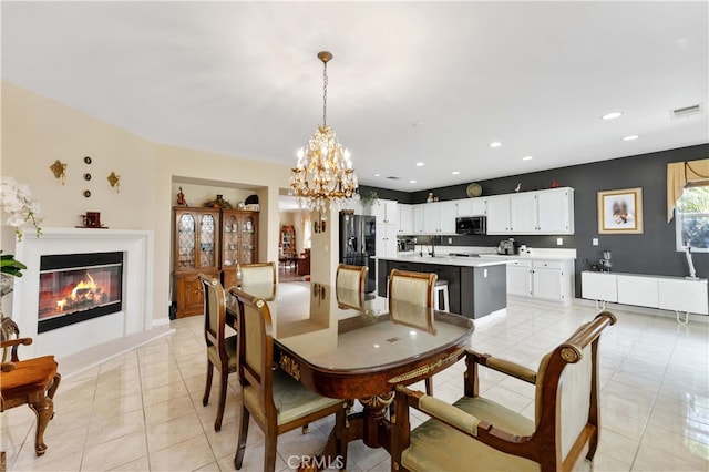 dining room with visible vents, a glass covered fireplace, recessed lighting, light tile patterned flooring, and a notable chandelier