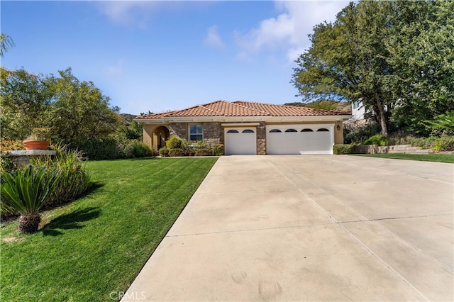 mediterranean / spanish-style house with a front yard, an attached garage, concrete driveway, stone siding, and a tiled roof