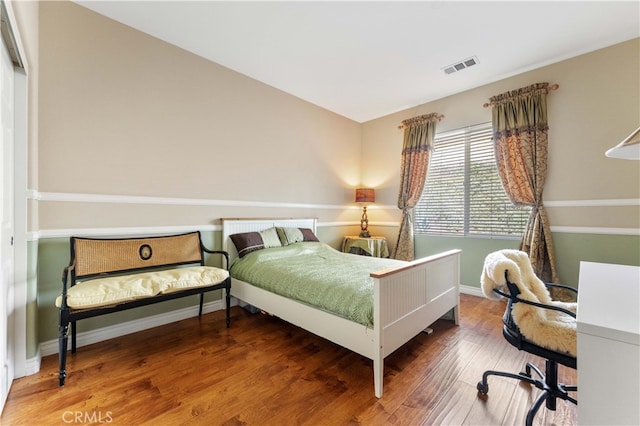 bedroom with visible vents, baseboards, and wood finished floors