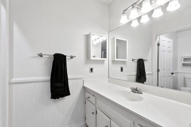 bathroom featuring vanity, toilet, and wainscoting