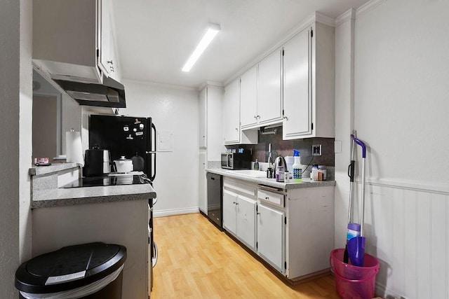 kitchen with black appliances, backsplash, white cabinetry, wainscoting, and light wood finished floors