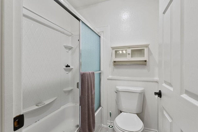 bathroom with toilet and bath / shower combo with glass door