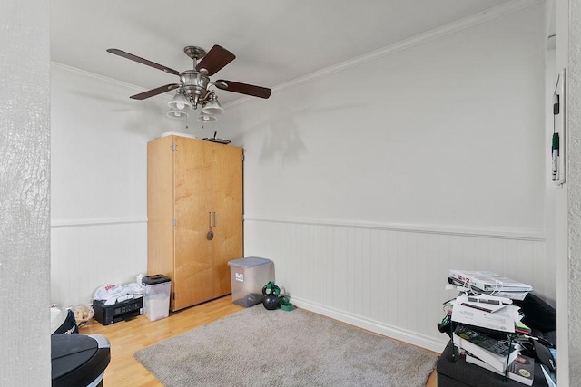 misc room with wood finished floors, a wainscoted wall, and ornamental molding