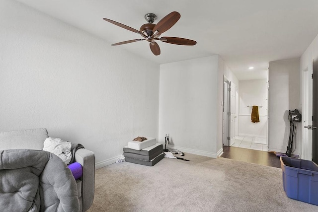 living area featuring baseboards, carpet, and a ceiling fan