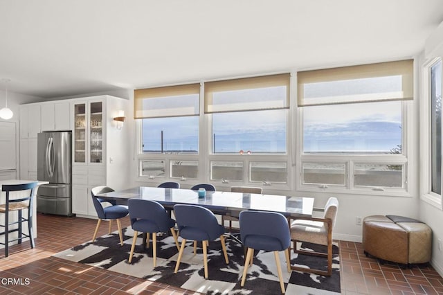 dining space with baseboards and brick floor