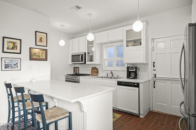 kitchen with tasteful backsplash, visible vents, a kitchen bar, appliances with stainless steel finishes, and a sink