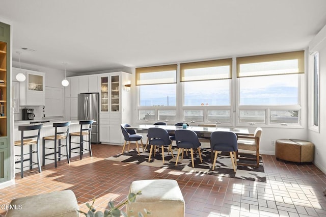 dining space featuring baseboards and brick floor