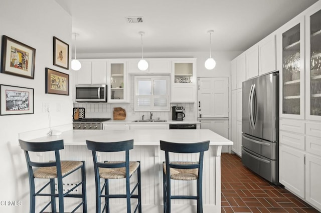 kitchen with tasteful backsplash, stainless steel appliances, light countertops, and a sink