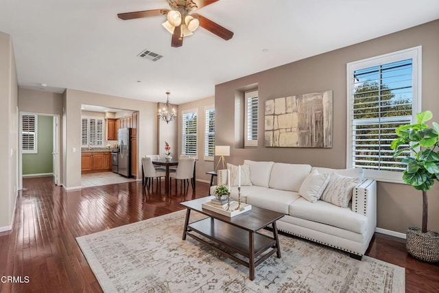 living room featuring ceiling fan with notable chandelier, hardwood / wood-style flooring, baseboards, and visible vents