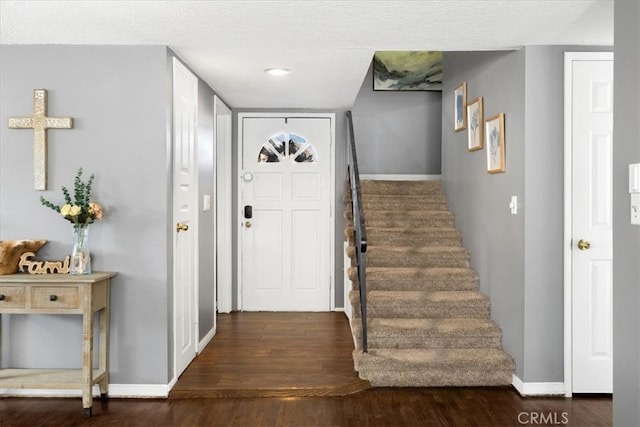 foyer entrance with stairs, wood finished floors, and baseboards