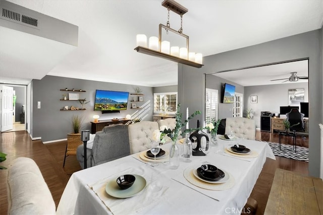 dining room featuring visible vents, baseboards, wood finished floors, and ceiling fan with notable chandelier