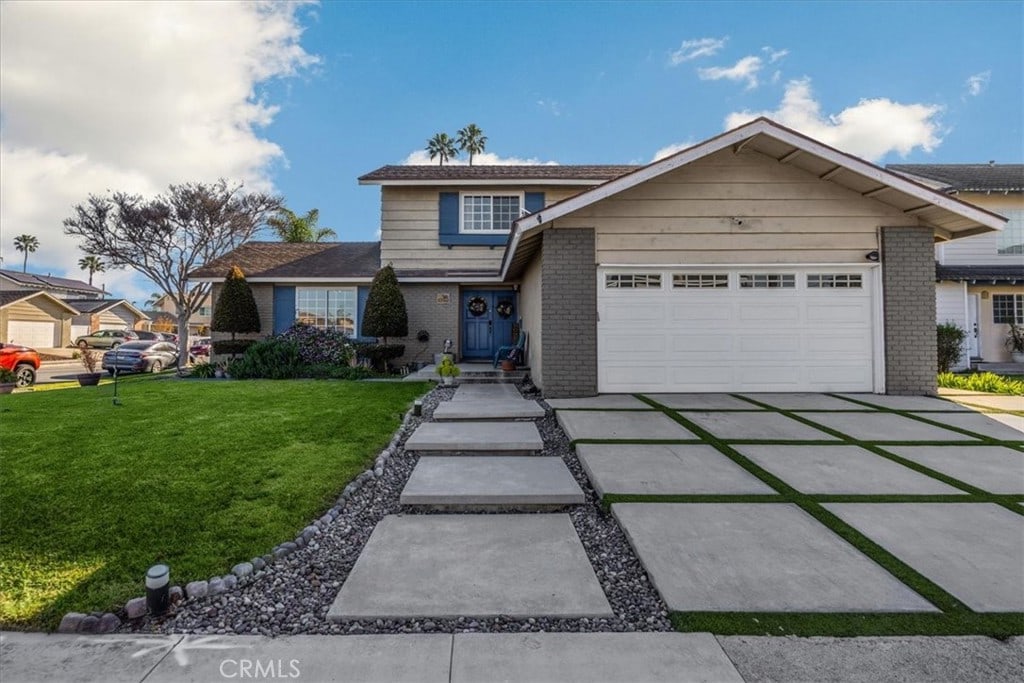 traditional-style home featuring a garage, brick siding, concrete driveway, and a front yard