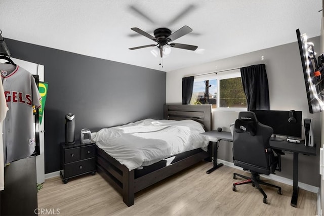 bedroom featuring light wood-style flooring, a ceiling fan, and baseboards