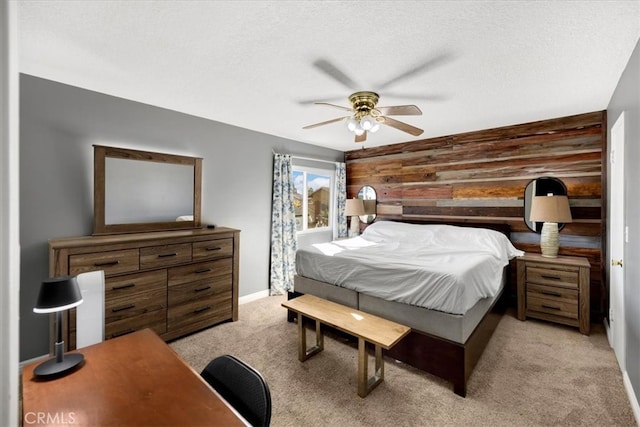 bedroom featuring a ceiling fan, a textured ceiling, wooden walls, baseboards, and light colored carpet