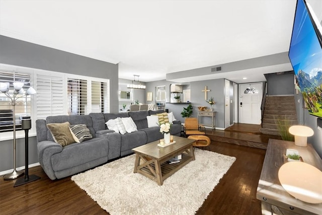 living room featuring stairs, wood finished floors, visible vents, and a chandelier