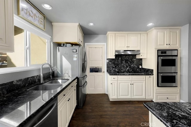 kitchen featuring dark wood-style flooring, a sink, decorative backsplash, appliances with stainless steel finishes, and under cabinet range hood