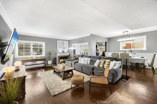 living room featuring a chandelier, a textured ceiling, wood finished floors, and a fireplace